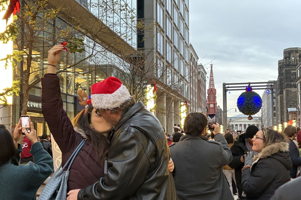 A couple kisses under a sprig of mistletoe in D.C. on Saturday. They were one of 1,435 couples to help set a Guinness World Record for most couples kissing under mistletoe.   (Washington Post )