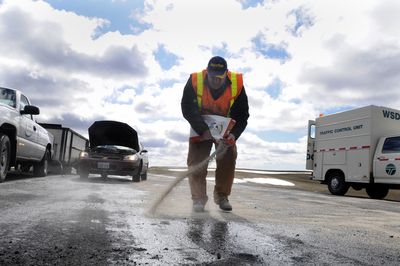 State worker Randy Kriebel spreads absorbent material to clean up a mess left by the tanker crash south of Spangle on U.S. Highway 195 Monday.  (Jesse Tinsley / The Spokesman-Review)