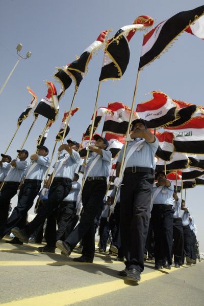 Iraqi police officers carry the country’s flags during a province handover ceremony in Diwaniyah, south of Baghdad.  (Associated Press / The Spokesman-Review)