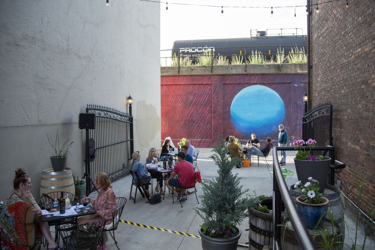 An entertainer was singing inside, but tables were full in the courtyard outside Barrister Winery in downtown Spokane after the popular wine bar opened for a Wednesday night on June 3. The winery spaces out the tables, has its staff wearing masks and offers hand sanitizer. (Jesse Tinsley/The Spokesman-Review)