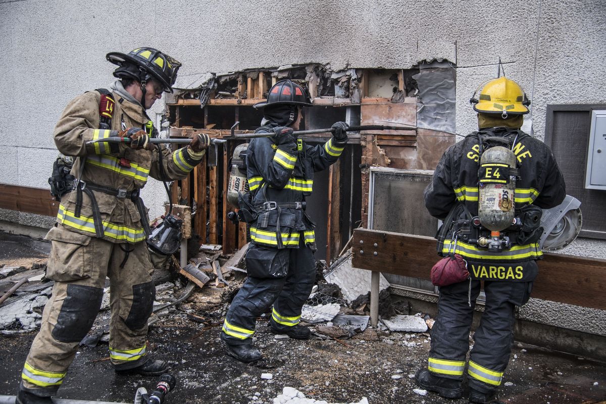 Spokane firefighters open up the outside wall at the Greetree Apartments, Oct. 21, 2016 after a blaze broke out in William Mendoza