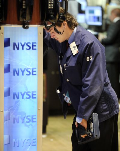 Trader Dudley Devine leans on a phone post at the New York Stock Exchange floor Monday as Wall Street suffered through another extraordinary and traumatic session. (Associated Press / The Spokesman-Review)