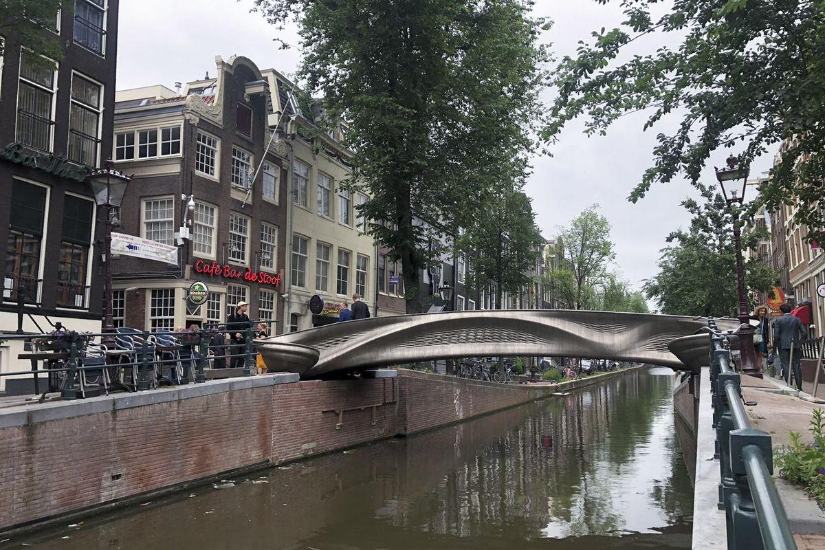 A steel 3D-printed pedestrian bridge spans a canal in the heart of the red light district in Amsterdam, Netherlands, Thursday, July 15, 2021. The distinctive flowing lines of the 12-meter (40-foot) bridge were created using a 3D printing technique called wire and arc additive manufacturing that combines robotics with welding.  (Aleksandar Furtula)