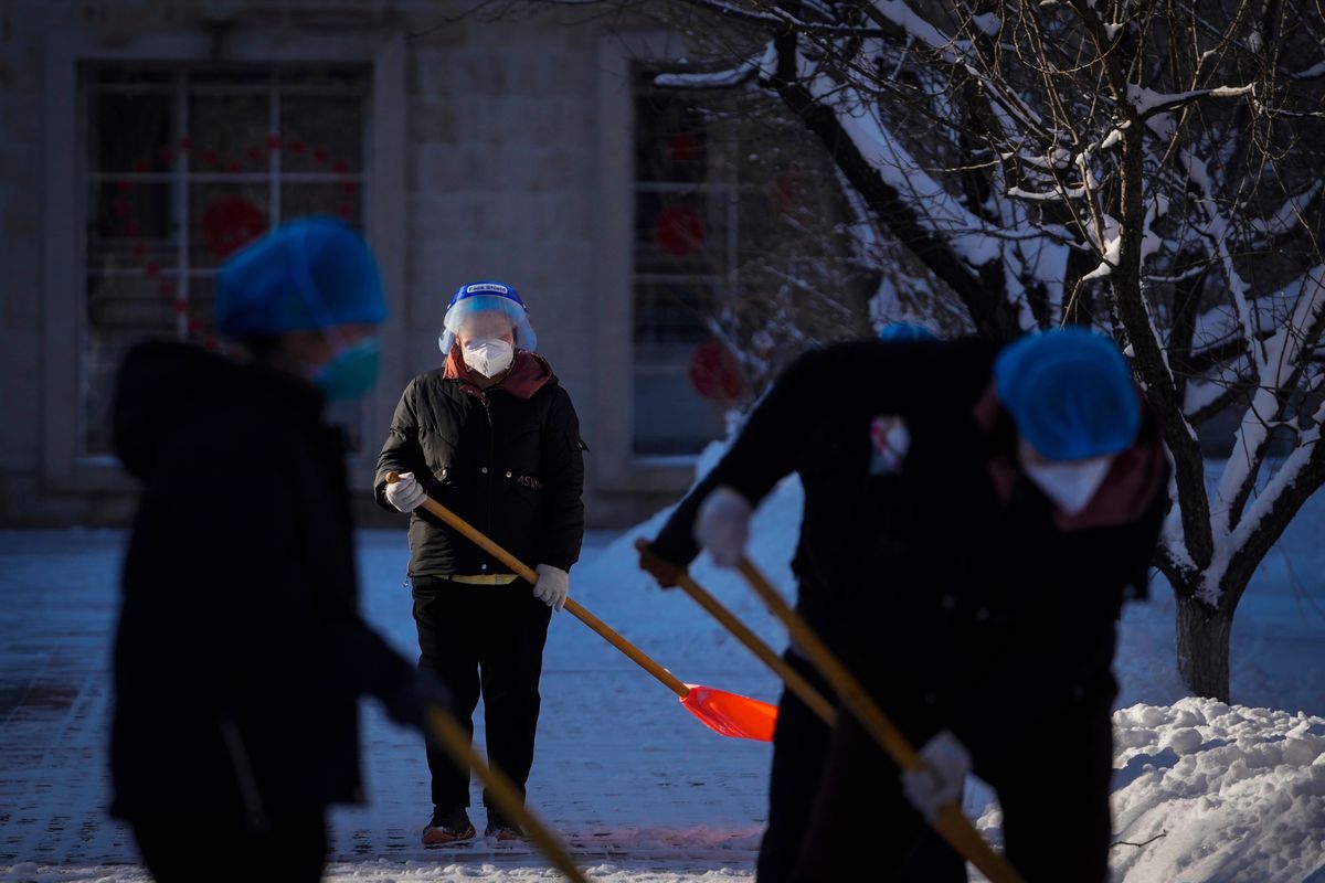 Workers wearing face shields and masks to help protect from the coronavirus clear the snow outside a health quarantine hotel Saturday in the Yanqing district of Beijing, as the capital city was hit by a snowstorm.  (Andy Wong)