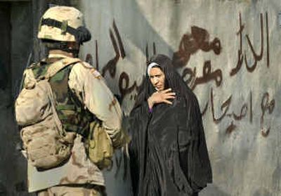 
An Iraqi woman walks past a U.S. Army patrol and a 