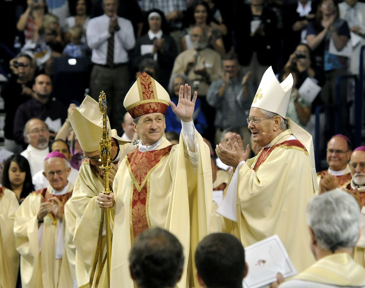 The Most Rev. Blase Cupich, center, waves to the crowd Friday  at the McCarthey Athletic Center at Gonzaga University  as he is installed as bishop of the Diocese of Spokane. He is flanked by the Most Rev. Alex J. Brunett, archbishop of Seattle, left, and the Most Rev. Pietro Sambi, apostolic nuncio to the United States. Cupich is the diocese’s sixth bishop since it was established in 1913.  (Dan Pelle)