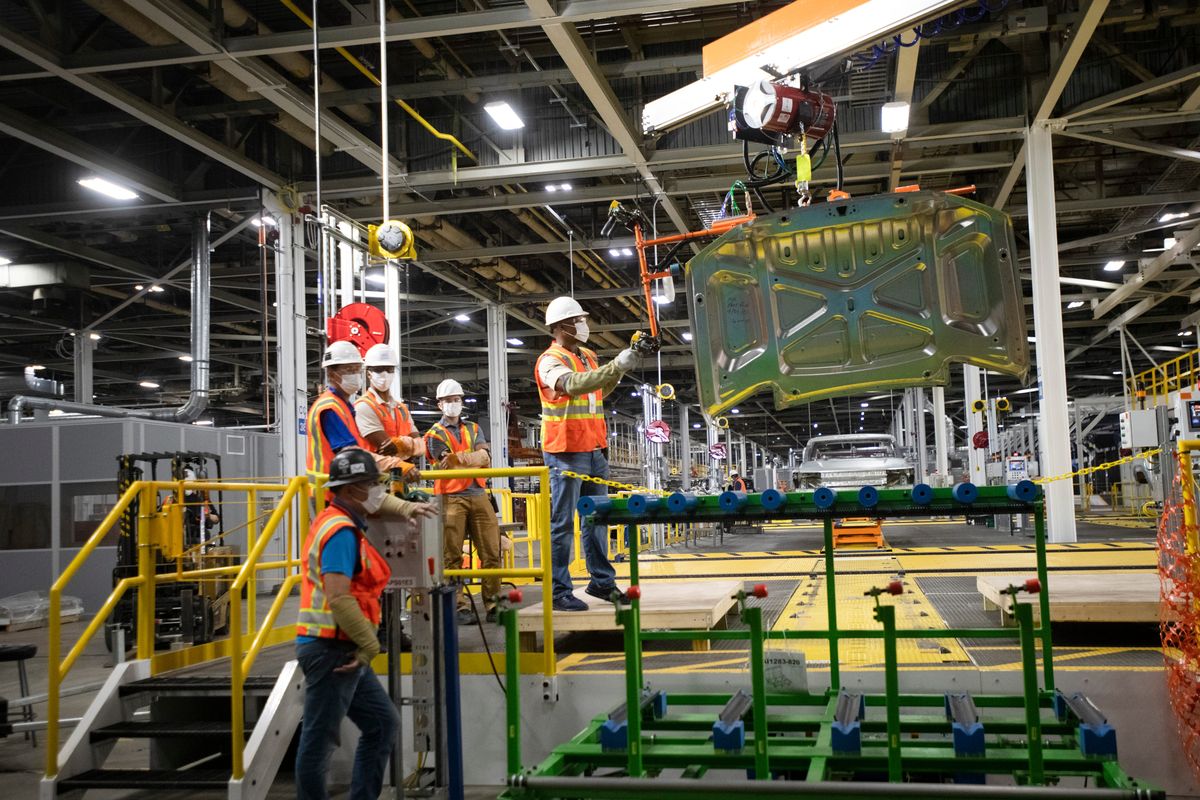 Auto workers troubleshoot the process of using a hoist to move car parts, in this case a hood, inside Factory Zero, General Motors’ Detroit Hamtramck Assembly Center.  (John T. Greilick/The Detroit News/TNS)