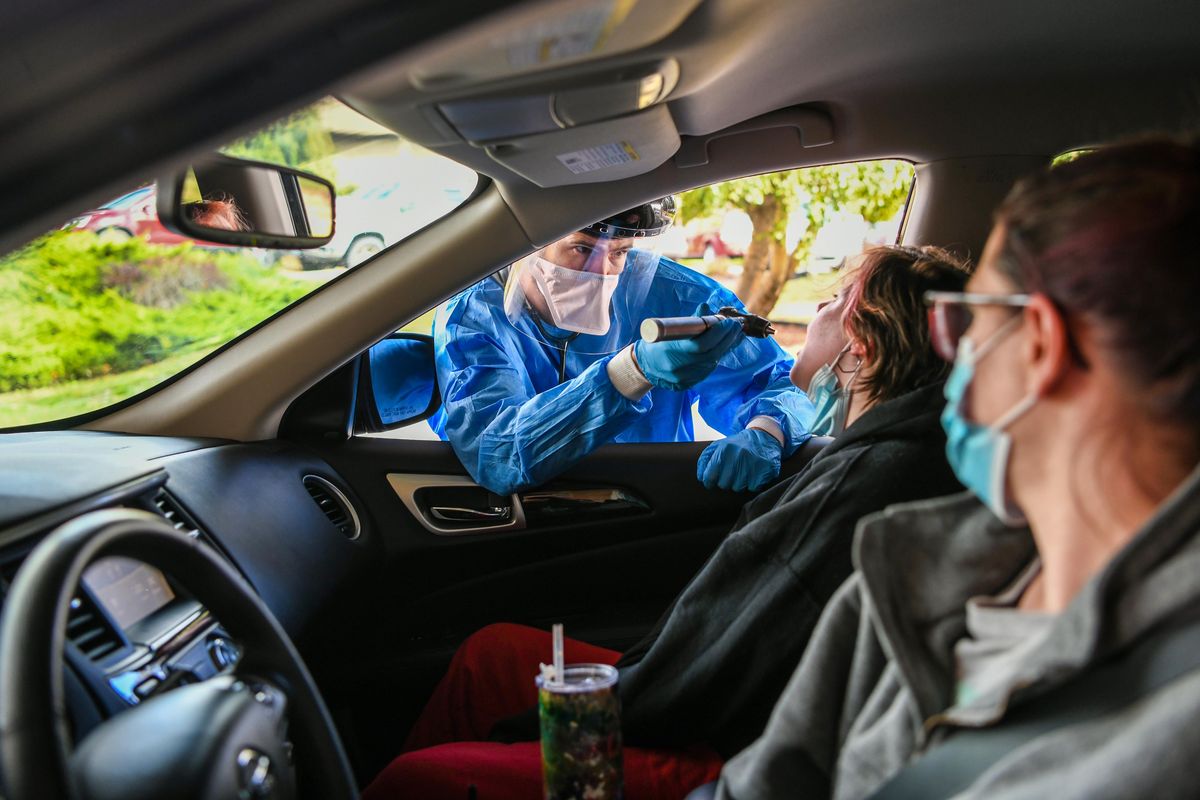 Dr. Ivan Gerlitz, of Providence Mount Carmel Hospital, administers a COVID-19 check to Abigail Sim, 11, as her mother Nicole watches from the driver’s seat at a drive-thru testing site Sept. 28 in Colville.  (DAN PELLE/THE SPOKESMAN-REVIEW)