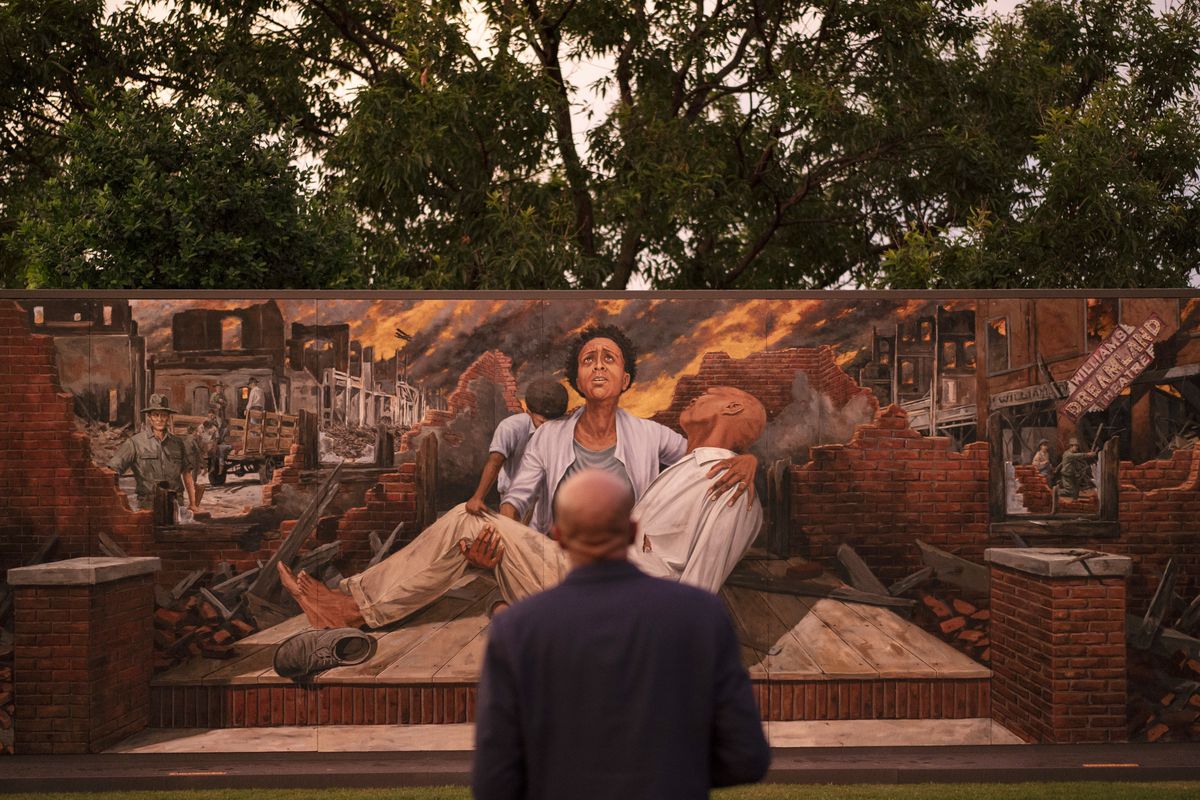 In this Thursday, May 27, 2021 photo, Darius Kirk looks at a mural depicting the Tulsa Race Massacre in the historic Greenwood neighborhood ahead of centennial commemorations of the massacre in Tulsa, Okla. The horror and violence visited upon Tulsa’s Black community in 1921 didn