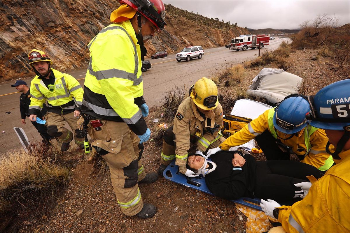 From left, San Bernardino County Fire Engineer Jeff Garcia, Capt. Dan Tellez, standing, paramedic Brian Bement, EMT Ray Barron and paramedic Eric Butikofer, right, with San Bernardino County Fire Protection District Station 53, stabilize a car accident victim who was thrown from her vehicle along I-15 at Mountain Pass in Nipton, Calif. (Genaro Molina/Los Angeles Times/TNS)