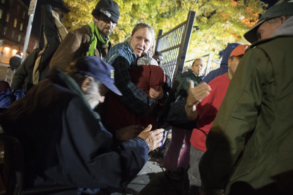 Theres some shuffling and grumbling as a man in a wheelchair gets to take priority in line at the House of Charity, Tuesday, Oct. 24, 2017. The lineup for a bed, even just a thin foam pad on the concrete floor, starts around 6 p.m., though the doors don’t open until about 7 p.m. most nights outside the homeless shelter. In the rain or extreme cold, the crowd can get restive or impatient, most everyone usually at least gets a place to sit up in a chair, out of the cold, if not a bed for the night. (Jesse Tinsley / The Spokesman-Review)