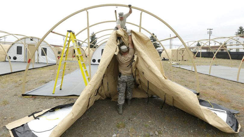 Staff Sgt. Andrew Waddell, top, and Master Sgt. Tyler Bates, bottom, both of the Washington Air National Guard based at Fairchild Air Force Base in Spokane, Wash., work to assemble temporary living structures at Joint Base Lewis-McChord in Washington state that will be used by troops taking part in a massive earthquake and tsunami readiness drill overseen by the Federal Emergency Management Agency on June 7-10, 2016. (AP Photo/Ted S. Warren)