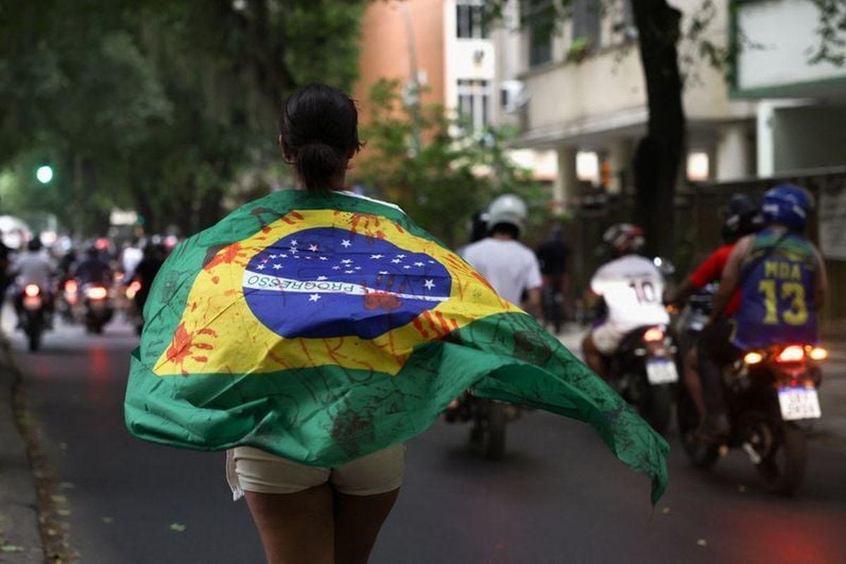 A woman draped in a Brazilian flag marked with fake blood stains protests, the day after a deadly police operation against drug trafficking at the favela do Penha, in Rio de Janeiro, Brazil October 29, 2025.    (Ricardo Moraes/Reuters)
