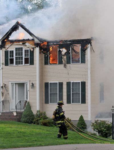 A firefighter outside a house in Plainville, Mass. (Associated Press)