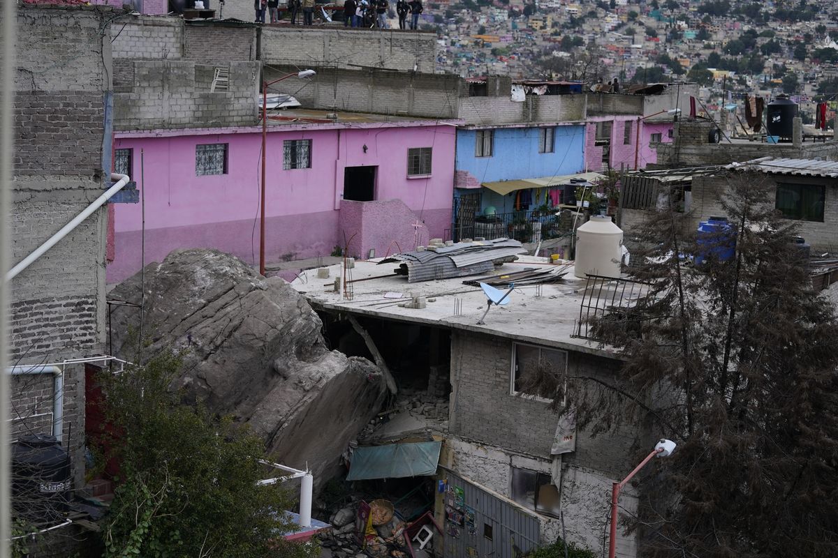 A boulder that plunged from a mountainside rests among homes in Tlalnepantla, on the outskirts of Mexico City, when a mountain gave way on Friday, Sept. 10, 2021. A section of mountain on the outskirts of Mexico City gave way Friday, plunging rocks the size of small homes onto a densely populated neighborhood and leaving at least one person dead and 10 others missing.  (Eduardo Verdugo)