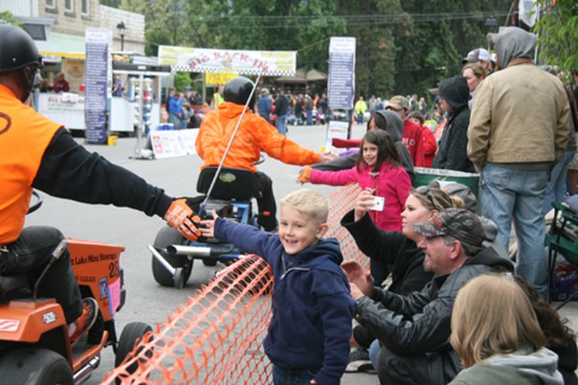 A delighted Brayden Quinn, 5, of Hayden high-fives the mower racers as they return to the pits during the 14th annual Big Back-In Sunday afternoon in Spirit Lake. (Devin Heilman/press)