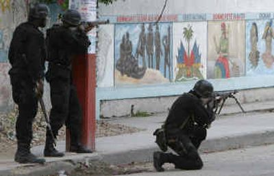 
A Haitian police officer fires his rifle close to one of the main entrances to the pro-Aristide slum of Bel Air, in Port-au-Prince, Haiti, on Friday. 
 (Associated Press / The Spokesman-Review)