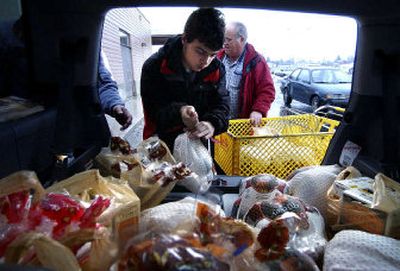 
John Cambareri, 16, picks up a frozen turkey, one of the many food items that he and his father John Cambareri  donated to the Sokane Valley Food Bank on Thursday. Food bank volunteer Mel Jones helps bring in the donations with a shopping cart. The food bank ran out of food on Wednesday, but a generous community restocked it in no time. 
 (Liz Kishimoto / The Spokesman-Review)