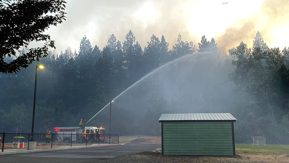 Fire crews spray trees behind Palisades Christian Academy on Friday.  (Alexandra Duggan / The Spokesman-Review)