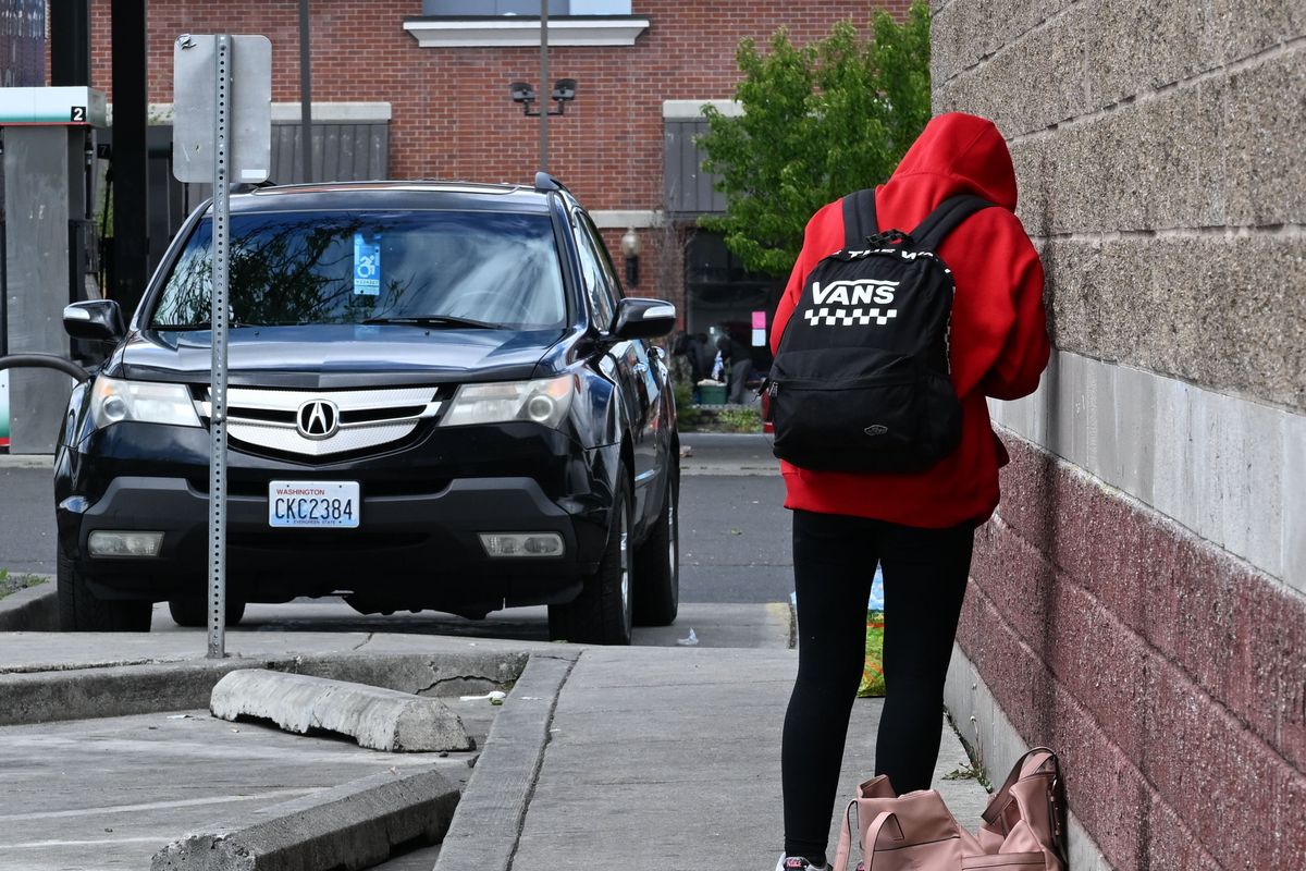 A woman smokes fentanyl in May 2023 on the side of the 7-Eleven convenience store at Second Avenue and Division Street in Spokane.  (COLIN MULVANY/THE SPOKESMAN-REVIEW)