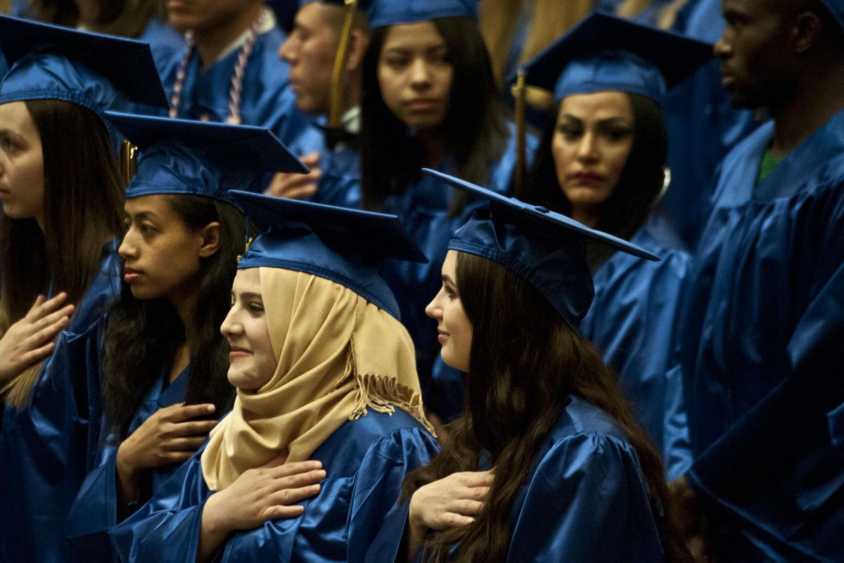 Asma Abdulmohsin, center, says the Pledge of Allegiance during the Spokane Community College Adult Education Commencement in Spokane on Tuesday, June 11, 2019. She is an ESL graduate from Iraq. (Kathy Plonka / The Spokesman-Review)