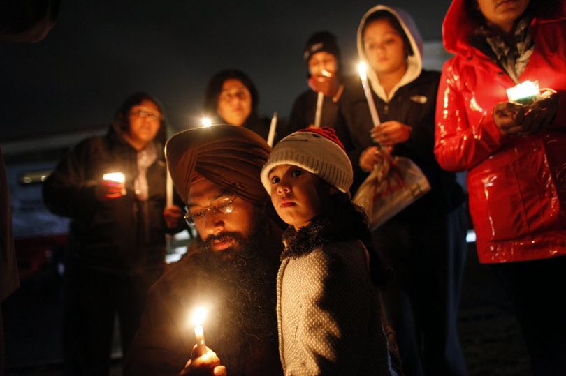 Eknoor Kaur, 3, stands with her father Guramril Singh during a candlelight vigil outside Newtown High School before an interfaith vigil with President Barack Obama, Sunday, Dec. 16, 2012, in Newtown, Conn. A gunman walked into Sandy Hook Elementary School in Newtown Friday and opened fire, killing 26 people, including 20 children.  (AP Photo/Jason DeCrow)