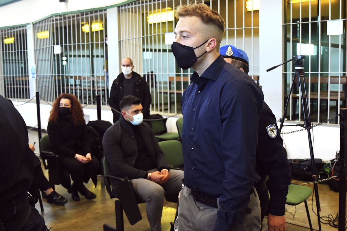 Finnegan Lee Elder walks past Rosa Maria Esilio, widow of slain Carabinieri military police officer Mario Cerciello Rega, background left, and Paolo Cerciello Rega, Mario’s brother, center, prior to a hearing Monday in the trial in which he and Gabriel Natale-Hjorth are accused of slaying a plainclothes officer while on vacation in Italy in July 2019.  (Alberto Pizzoli)