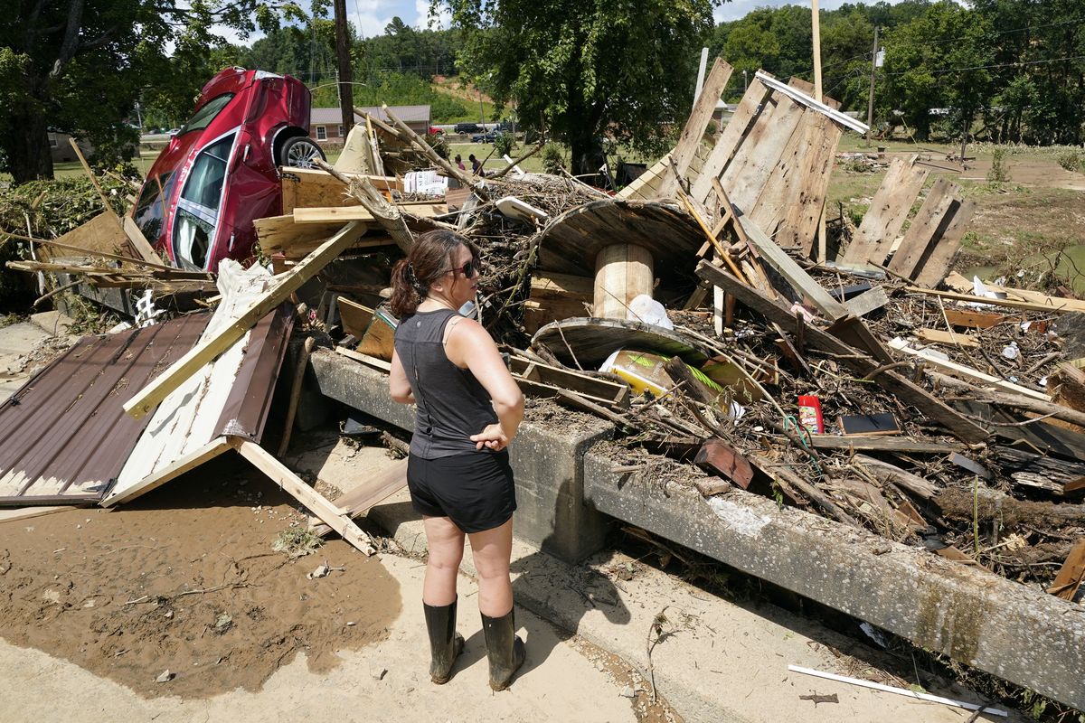 A woman looks at debris washed up against a bridge over a stream Sunday, Aug. 22, 2021, in Waverly, Tenn. Heavy rains caused flooding Saturday in Middle Tennessee and have resulted in multiple deaths as homes and rural roads were washed away.  (Mark Humphrey)
