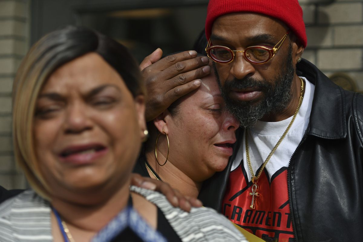 Antoinette Walker cries on the shoulder of Frank Turner as Penelope Scott speaks to the media during an interview at the corner of 10th and K street in Sacramento, Calif., on Monday, April 4, 2022. Walker is the older sister of De