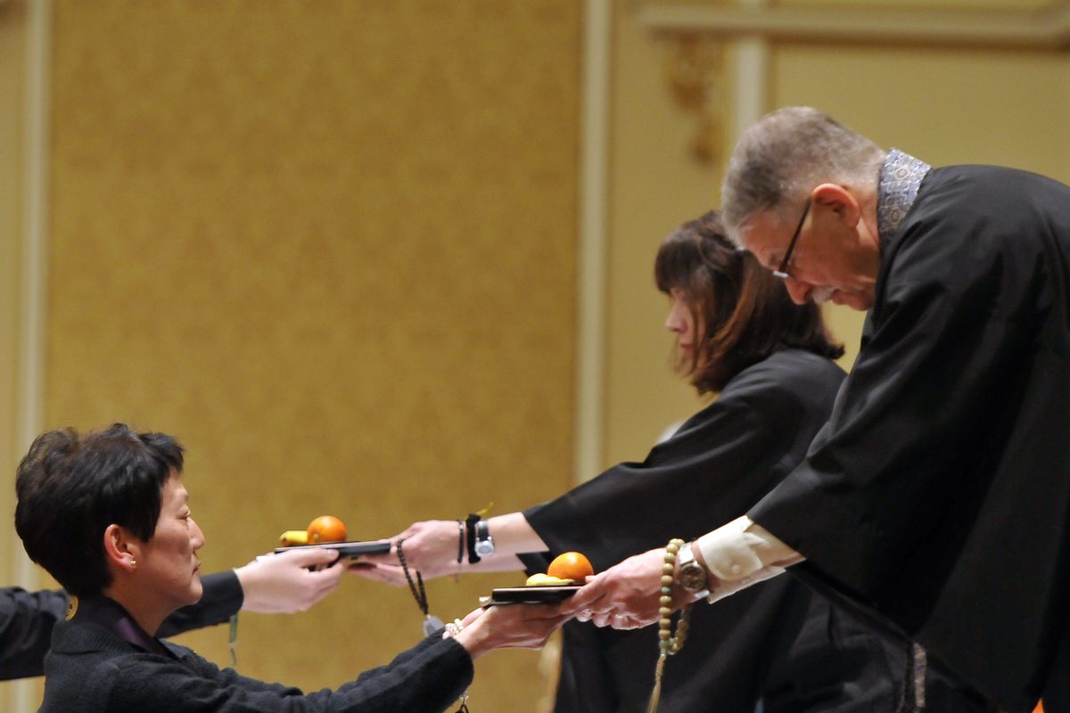 Sensei Paul Vielle, right, accepts an offering of fruit Saturday during the Buddhist conference. (Jesse Tinsley)