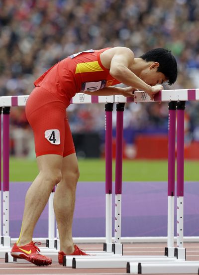 China’s Liu Xiang kisses hurdle after falling and injuring Achilles tendon. (Associated Press)