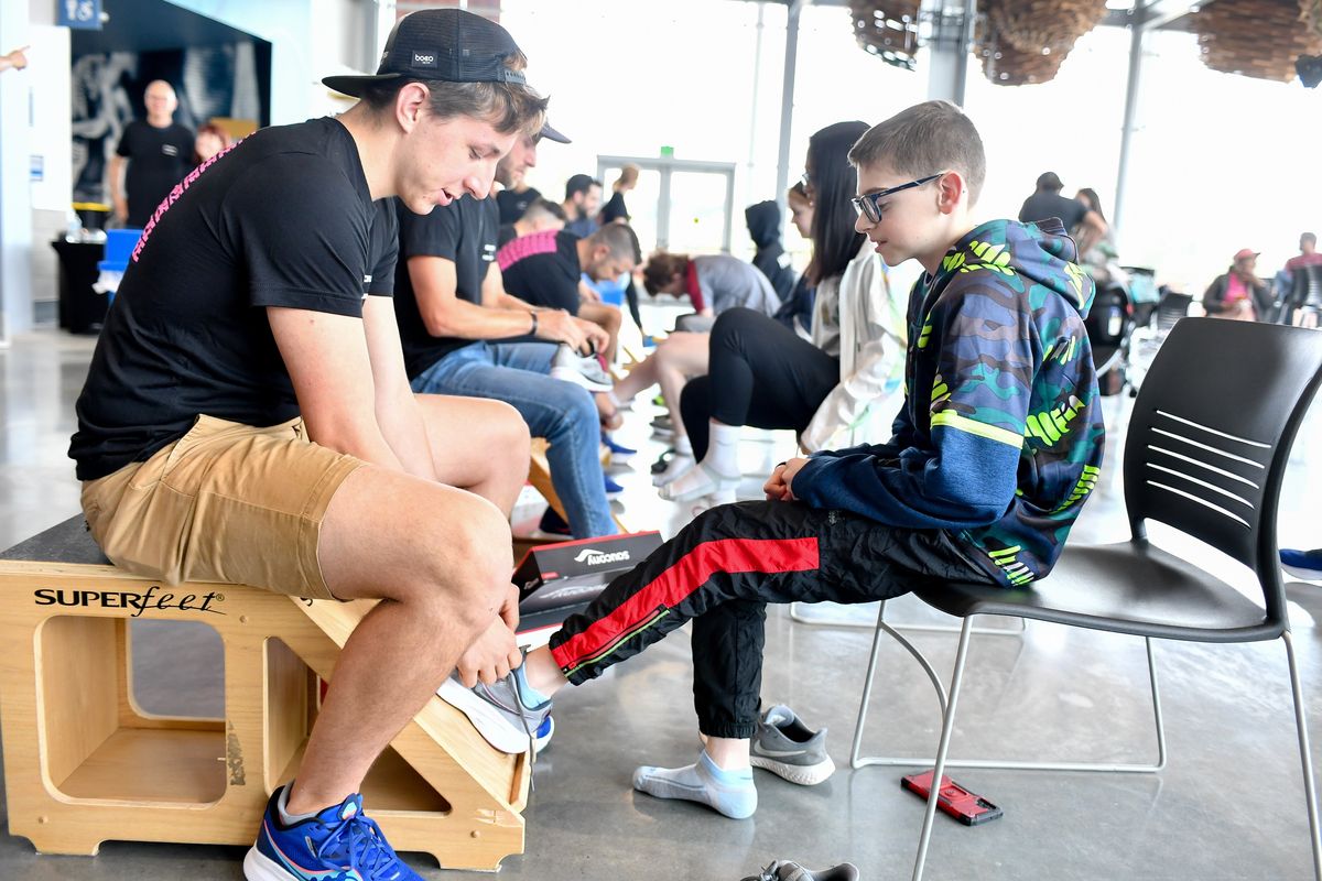 Tristan Buder, a Fleet Feet store manager from Schererville, Ind., fits youngster Daniel Whitacre for a new pair of Saucony running shoes during a shoe giveaway for local runners on Monday.  (Tyler Tjomsland/The Spokesman-Review)