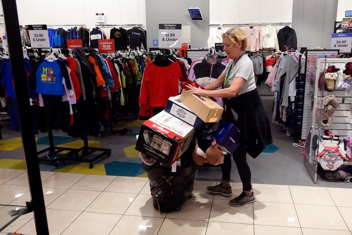 A shopper pushes her cart full of items down an isle during a Black Friday sale at Macy