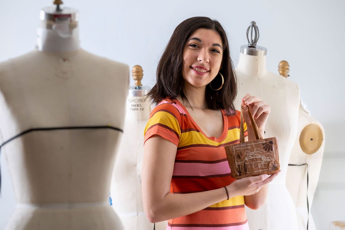 Washington State University sophomore Rowena Gonzalez holds a purse she made out of dried bacterial cellulose from kombucha on Thursday in Pullman. The purse includes an image of a classic Pueblo village that Gonzalez created.  (Geoff Crimmins/For The Spokesman-Review)