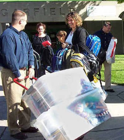   Jacob Borg, left, University of Phoenix Spokane campus enrollment manager, and Paul Green, campus director, far right, deliver school supplies and backpacks for students at Garfield Elementary. 
 (Kandis Carper / The Spokesman-Review)