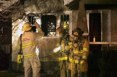 
Spokane firefighters clean up after a house fire in the 1500 block of West Sharp Avenue on Monday. The blaze was confined to a bedroom, but the rest of the house suffered smoke damage. 
 (Christopher Anderson / The Spokesman-Review)