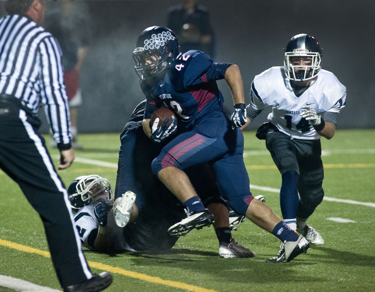 Mt. Spokane’s Mike Schupp blasts by Gonzaga Prep’s Conner McKenna, left, and Jack Padon to score one of his two touchdowns. (Dan Pelle)