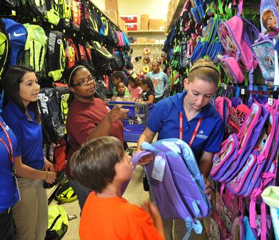 Tori Smith, center, director of the Southwest Branch of the Boys and Girls Club in Wichita Falls, Texas, helps several club members pick out new backpacks for school last week. (Associated Press)