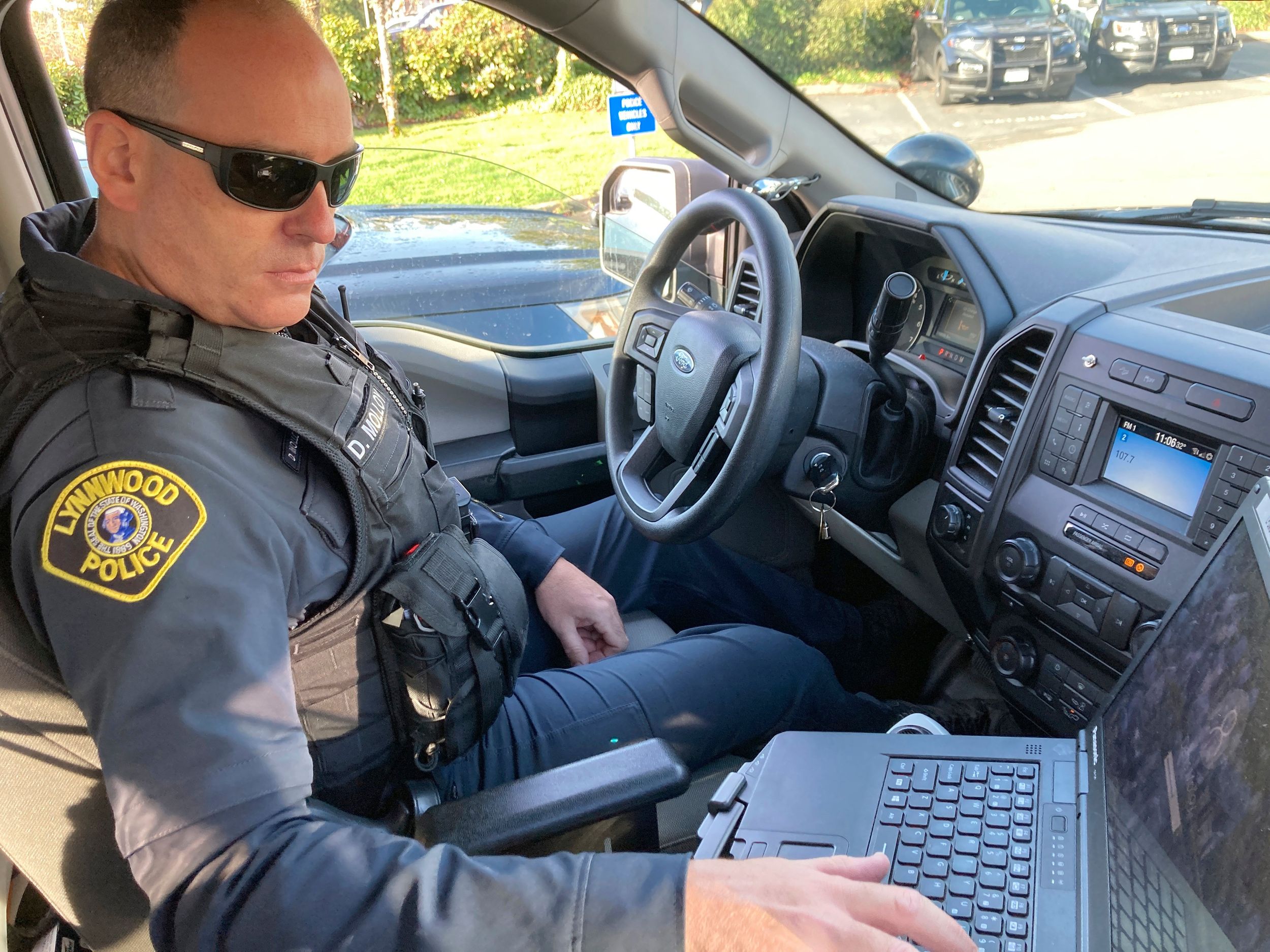 FILE - Lynnwood police Officer Denis Molloy works in his vehicle, Wednesday, Nov. 17, 2021, in Lynnwood, Wash. Molloy is part of the Lynnwood Police Department's community health and safety section. Washington Gov. Jay Inslee has signed two bills fixing parts of a sweeping package of police reform measures that lawmakers passed last year. One makes clear officers may use force to help detain or transport people in behavioral health crisis, while the other fixes an oversight that seemed to inadvertently prohibit police departments from possessing certain less-lethal weapons.  (Gene Johnson)