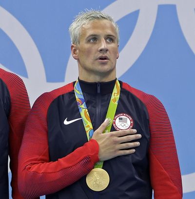 In this Aug. 10, 2016, file photo, Ryan Lochte listens to the national anthem after being awarded a gold medal during the ceremony for the men's 4x200-meter freestyle relay final at the 2016 Summer Olympics in Rio de Janeiro, Brazil. Lochte is banned from swimming through next June and will forfeit $100,000 in bonus money that went with his gold medal at the Olympics, part of the penalty for his drunken encounter at a gas station in Brazil during last month's games. The U.S. Olympic Committee and USA Swimming announced the penalties Thursday. (Michael Sohn / Associated Press)