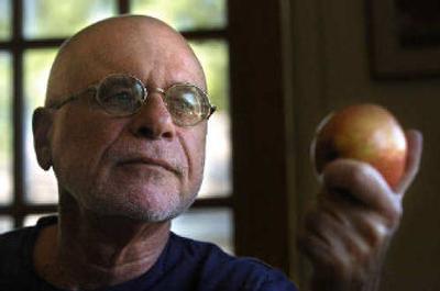 
 Robert Klein holds an apple in Albuquerque, N.M. Klein has developed a sticker to help growers know when the fruit they produce has begun ripening. 
 (Associated Press / The Spokesman-Review)