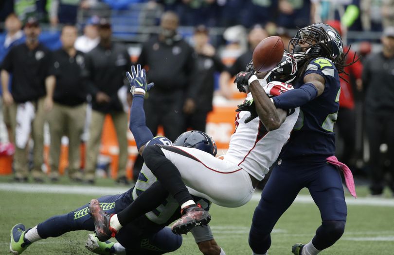 Seahawks’ Richard Sherman, right, and Earl Thomas (obscured) break up a pass intended for wide receiver Julio Jones that ensured Seattle’s victory in October. (Elaine Thompson / Associated Press)