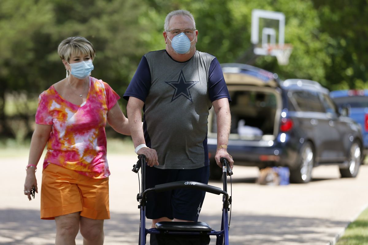 Terri Donelson, left, and her husband, Stephen, walk up their driveway to see friends and family awaiting him at his home in Midlothian, Texas on Friday, June 19, 2020, after his 90-day stay in the Zale Hospital on the UT Southwestern Campus. Donelson’s family hadn’t left the house in two weeks after COVID-19 started spreading in Texas, hoping to shield the organ transplant recipient. Yet one night, his wife found him barely breathing, his skin turning blue, and called 911.  (Tony Gutierrez)