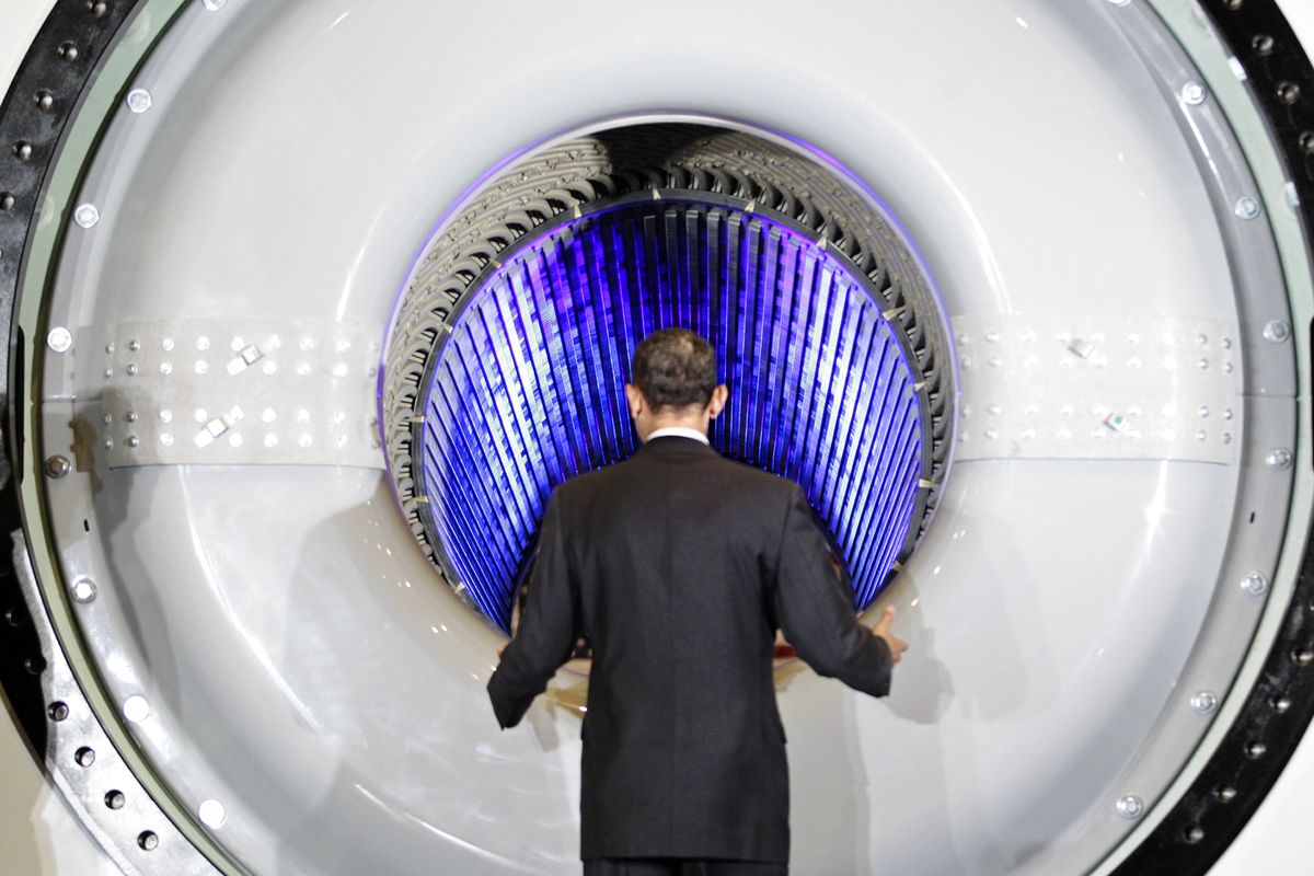 President Barack Obama peers into a high-tech hydrogen-cooled generator being manufactured for a power station in Kuwait as he tours a GE plant Friday in Schenectady, N.Y., to talk about clean energy and green jobs.  (Associated Press)
