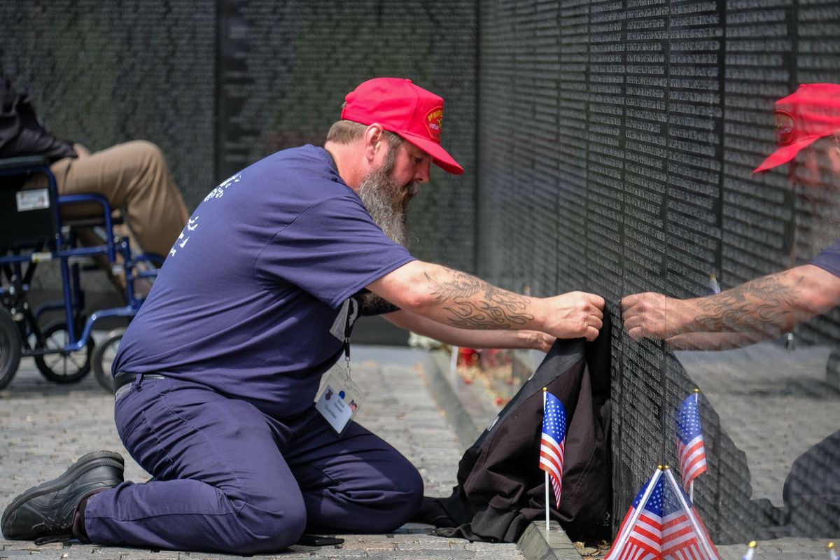 Bruce Hansen, of Marysville, Washington, lays down a jacket that belonged to his father, Vietnam War veteran David Hansen, at the Vietnam Veterans Memorial in Washington, D.C., during a visit organized by Inland Northwest Honor Flight on Tuesday. David Hansen, who was scheduled to join an Honor Flight trip two years earlier that was delayed by the COVID-19 pandemic, died in February.  (Orion Donovan-Smith/The Spokesman-Review)