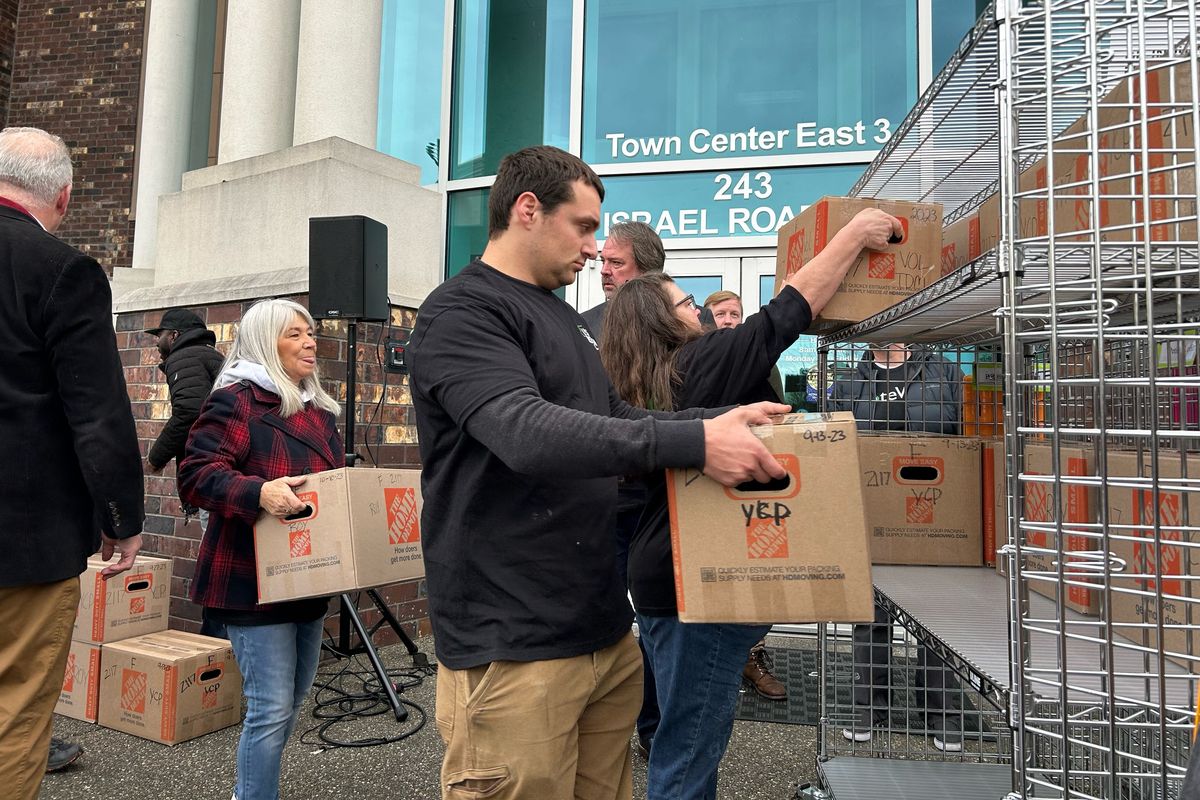 Supporters of a political effort to repeal Washington’s Climate Commitment Act load boxes full of signatures supporting Ballot Initiative 2117 onto carts to be wheeled into the Washington Secretary of State’s office in Tumwater on Nov 21.  (Ellen Dennis / The Spokesman-Review)
