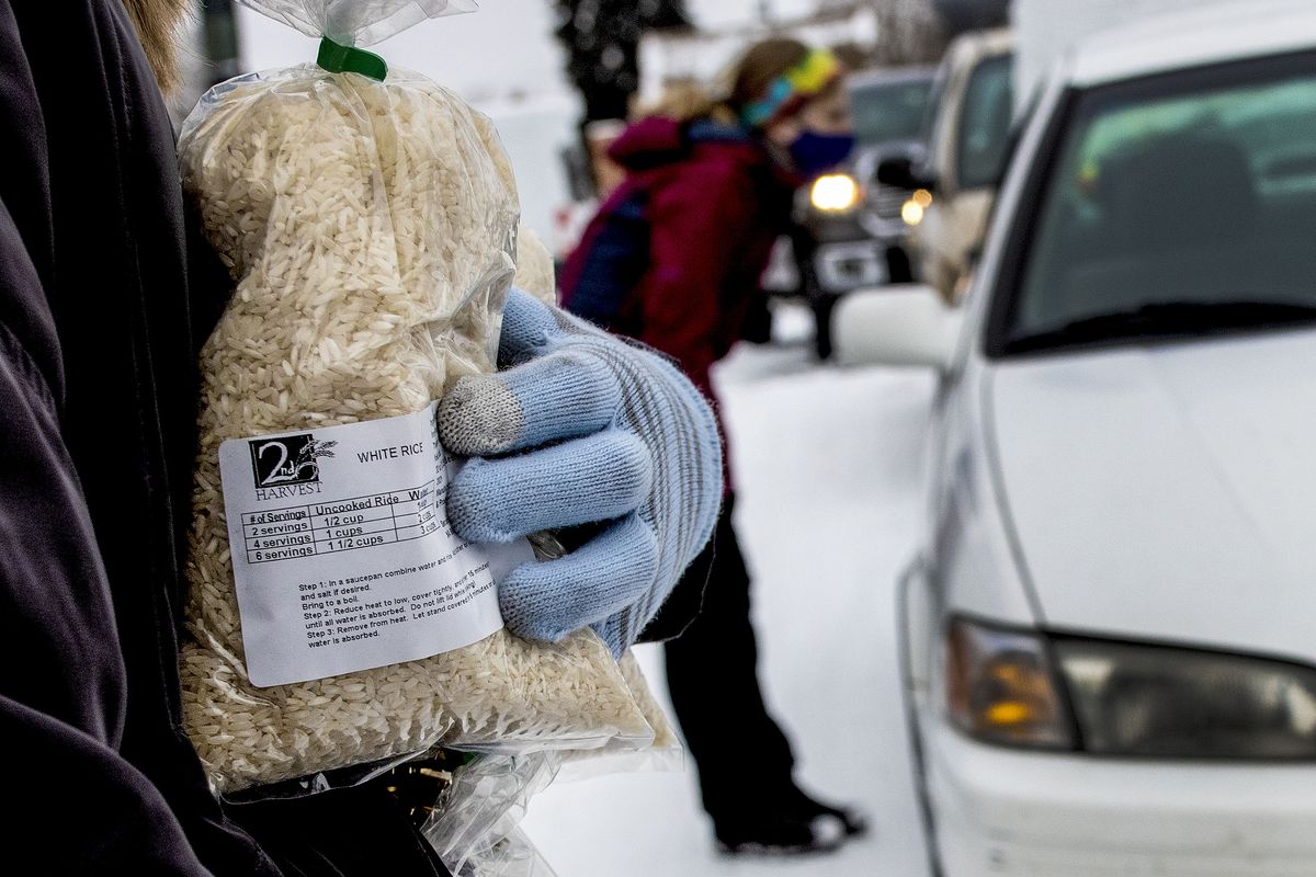 Maddy Olson of Communities in Schools gives away bags of rice during the Second Harvest Mobile Market food distribution Monday at Rogers High School in Spokane.  (Kathy Plonka/The Spokesman-Review)