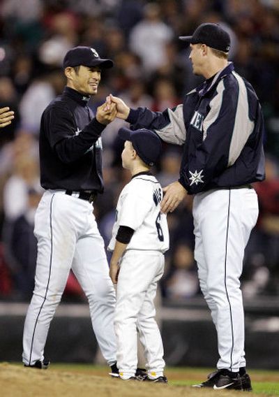 
Ichiro Suzuki, left, whose 4-for-5 night shot him past 200 hits for a fifth straight season, and Dan Wilson, who played in his last game, share a moment with Wilson's son, Eli, 6, following the Mariners' 4-1 win over Oakland on Friday night in Seattle.  
 (Associated Press / The Spokesman-Review)