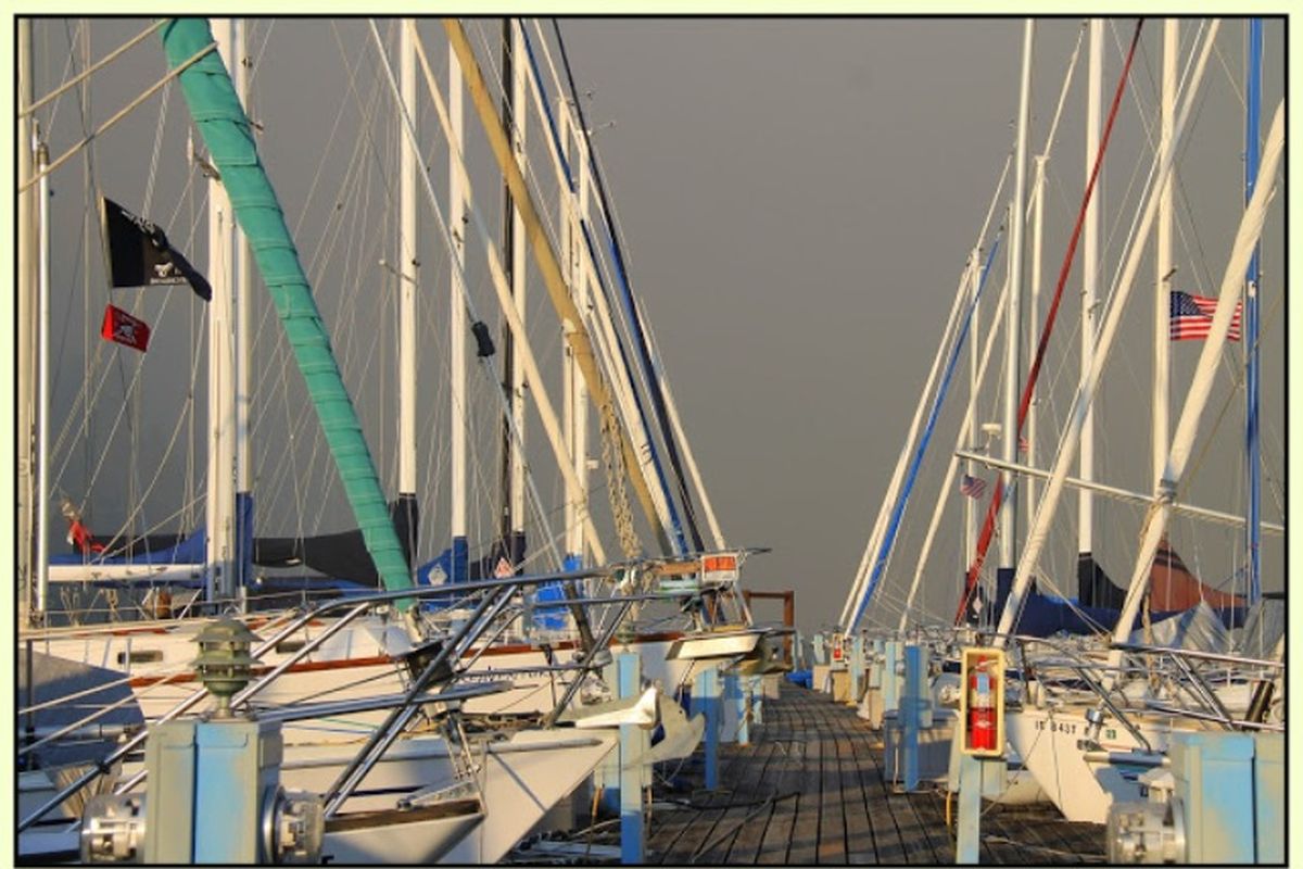 Sailboats tied up in the foreground, dark smoke in the background. (Marianne Love/Slight Detour)