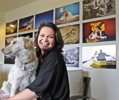 Spokane photographer Suwanee Lennon holds her dog Nova in her living room, framed by some of her images. (Christopher Anderson)